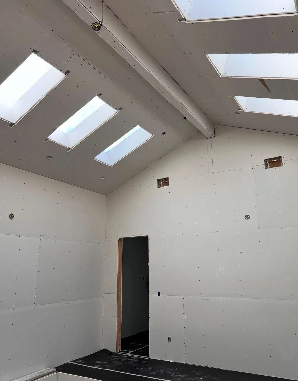 A sloped ceiling with skylights and recessed light openings.