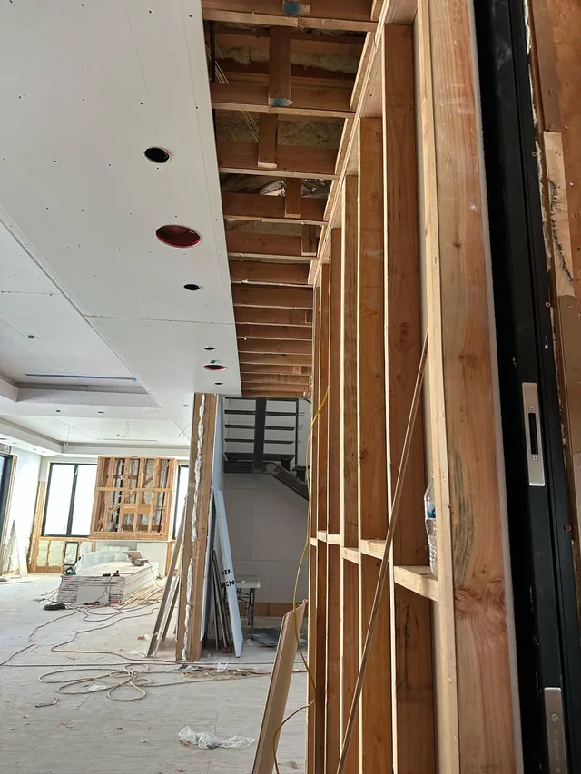 Exposed wood wall framing beside a ceiling partially covered with drywall.
