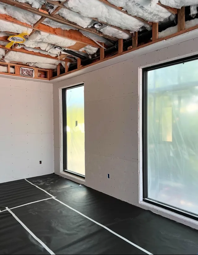 Wall surfaces and exposed ceiling framing alongside tall windows.
