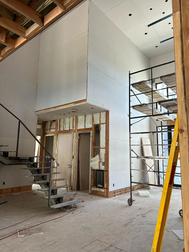 A double-height interior with wall and ceiling surfaces in progress.