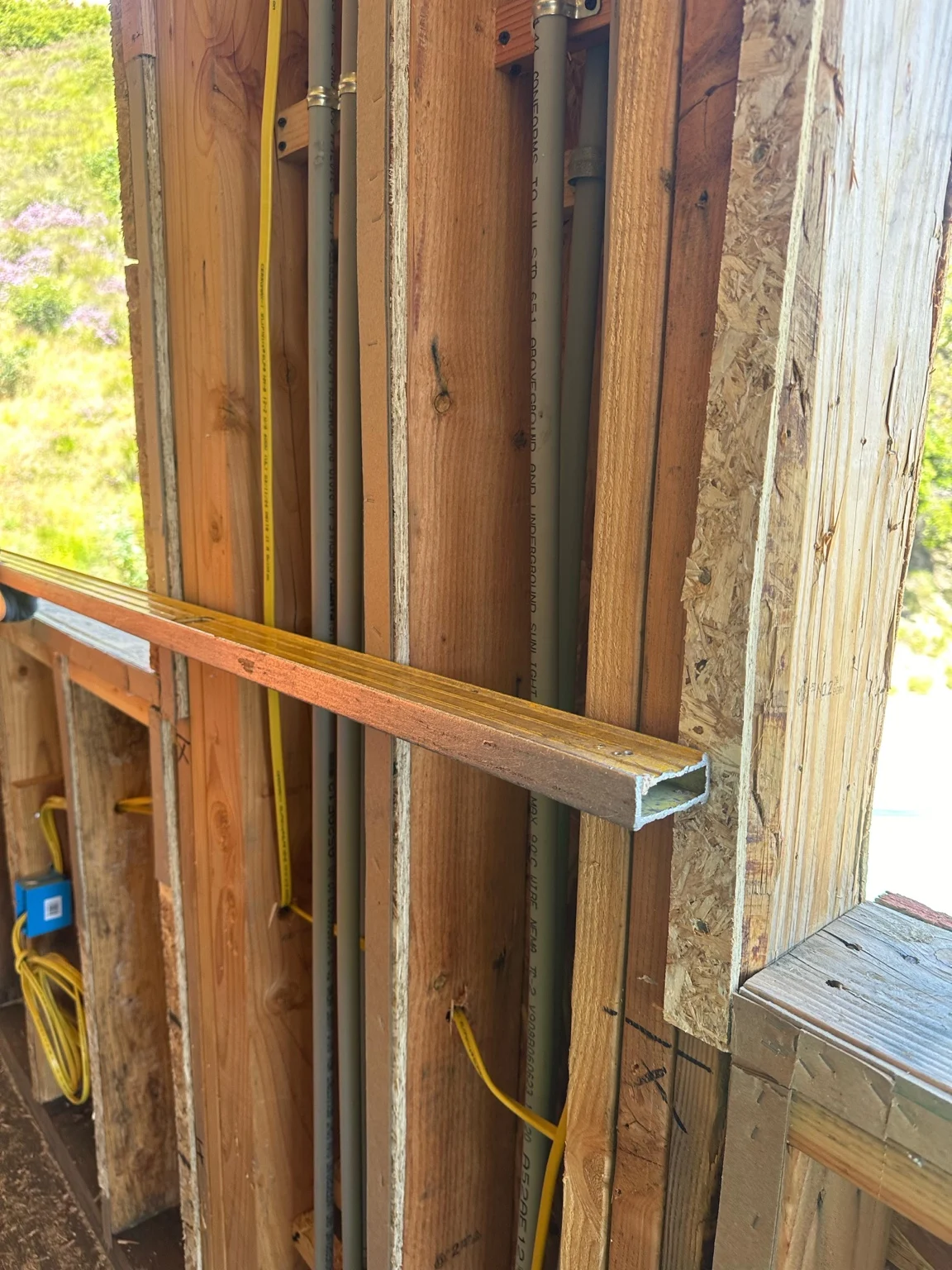 A straightedge checking exposed wood framing beside a window.